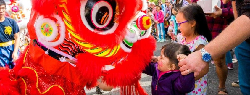 Full color photo of Crowds at the Eden Center during the Dragon Festival with two kids meeting a dragon.
